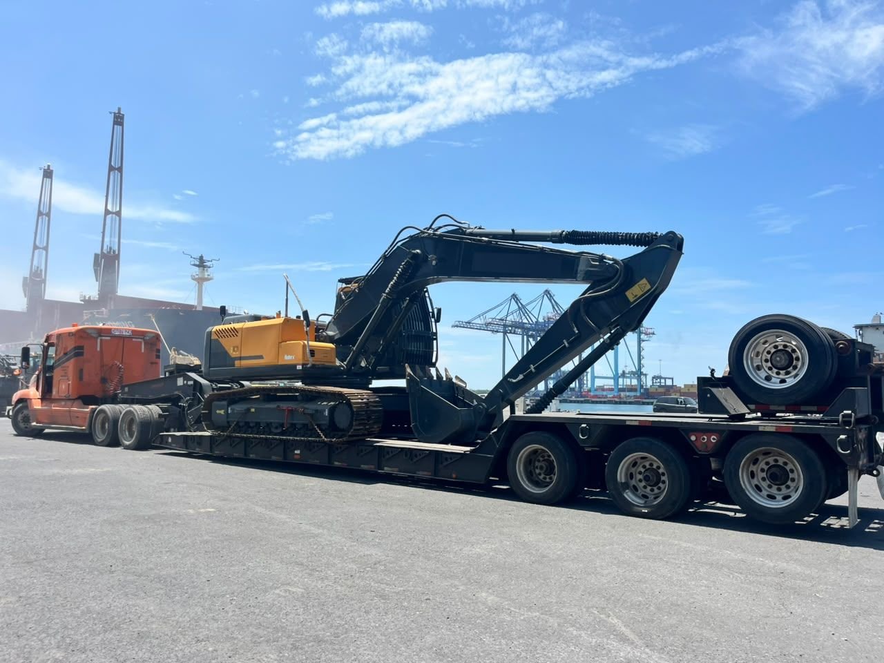 Excavadora en lowboy en el puerto